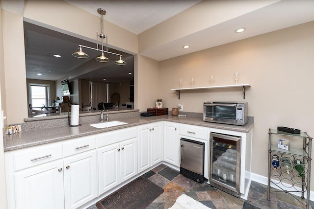 kitchen featuring wine cooler, sink, decorative light fixtures, and white cabinets