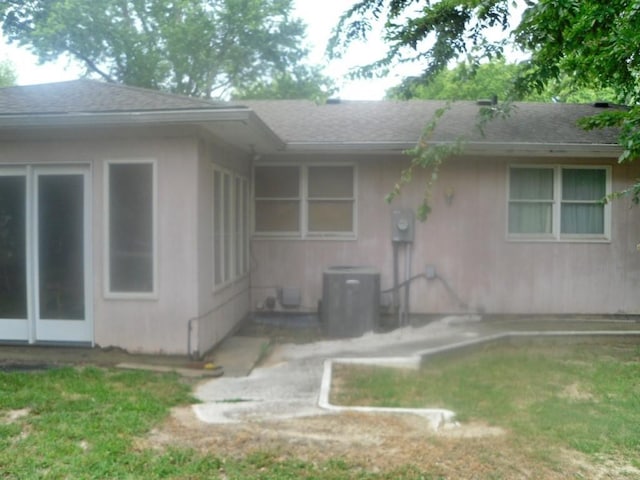 back of house with cooling unit and a lawn