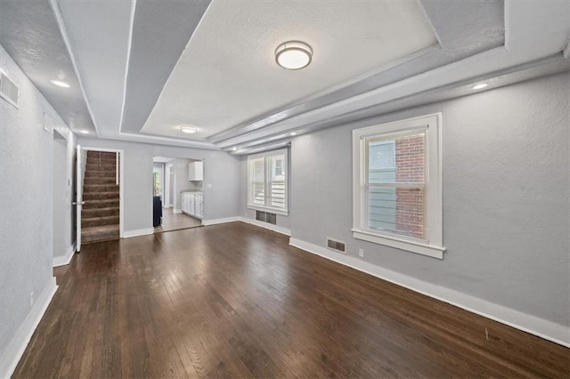 unfurnished living room featuring wood-type flooring and a tray ceiling