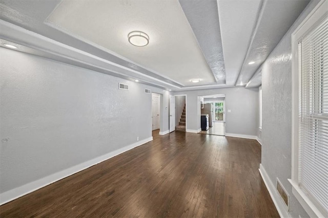 spare room featuring dark wood-type flooring and a tray ceiling