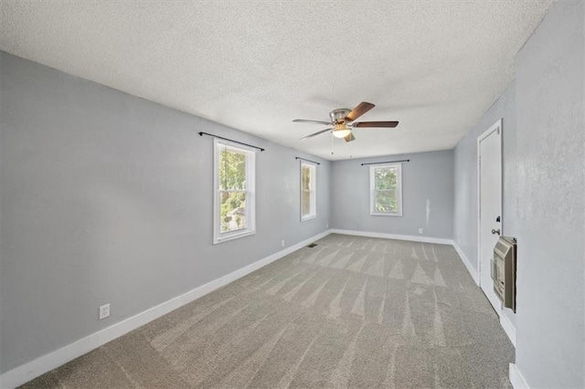 carpeted spare room with a textured ceiling, ceiling fan, and heating unit