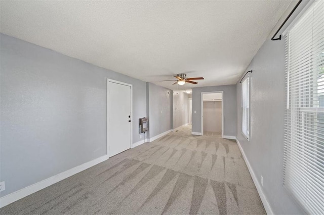 spare room featuring a textured ceiling, light colored carpet, heating unit, and ceiling fan