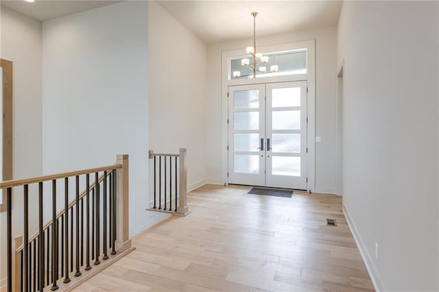 entryway with light wood-type flooring, visible vents, french doors, baseboards, and a chandelier