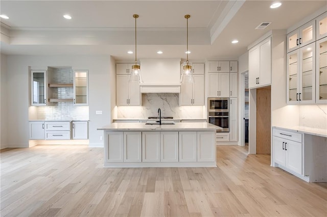 kitchen with visible vents, a tray ceiling, stainless steel appliances, light wood-style floors, and white cabinets