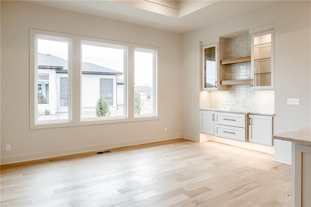 unfurnished living room with light wood-style flooring, baseboards, and visible vents