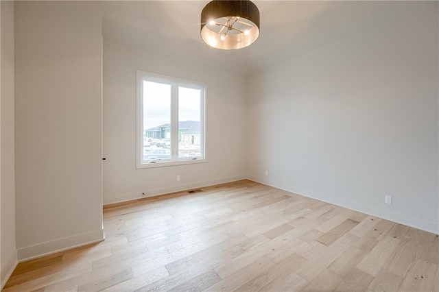 unfurnished room featuring baseboards, visible vents, and light wood finished floors