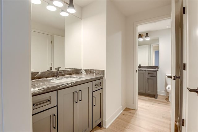 bathroom with vanity, toilet, wood finished floors, and baseboards