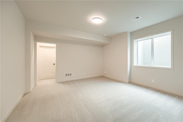 unfurnished room with visible vents, baseboards, and light colored carpet