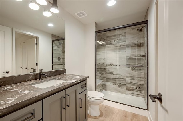 full bathroom featuring visible vents, toilet, wood finished floors, a shower stall, and vanity