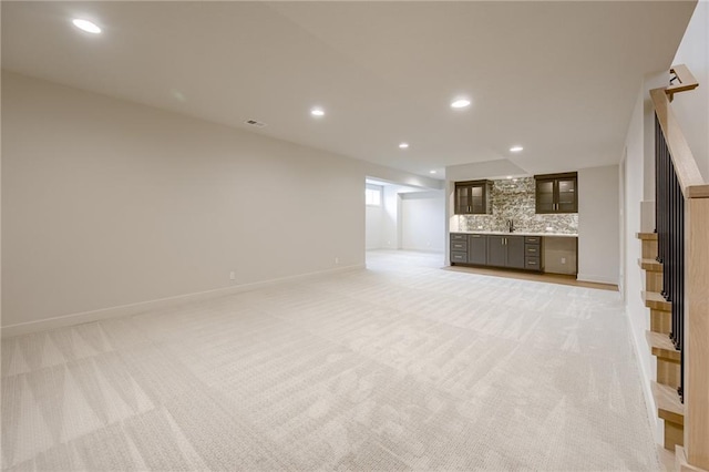 unfurnished living room with recessed lighting, light colored carpet, and baseboards