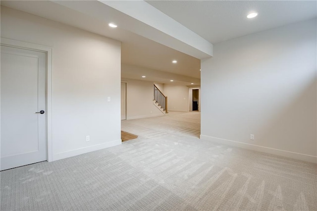 unfurnished room featuring recessed lighting, light colored carpet, and stairs