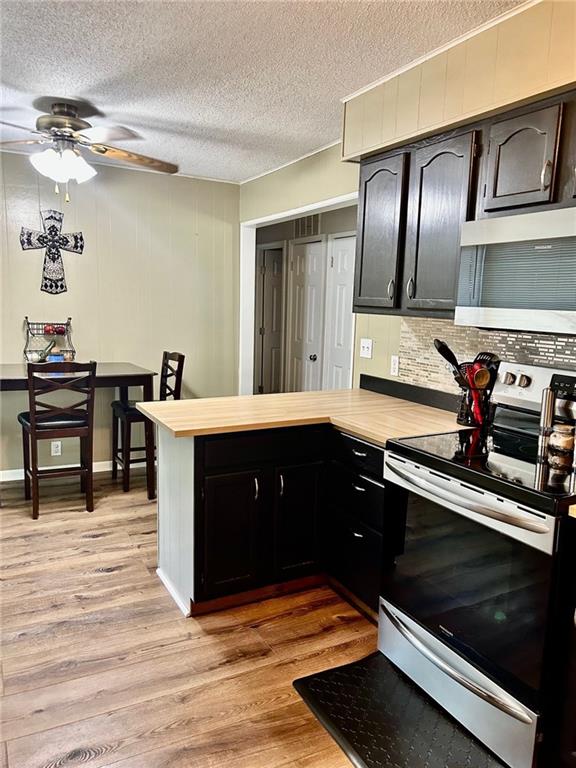 kitchen featuring kitchen peninsula, stainless steel appliances, a textured ceiling, and light hardwood / wood-style floors