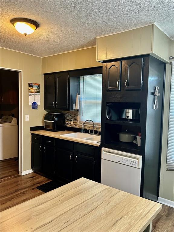 kitchen with dishwasher, sink, washer / clothes dryer, hardwood / wood-style floors, and a textured ceiling