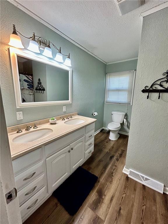 bathroom with vanity, a textured ceiling, crown molding, hardwood / wood-style floors, and toilet