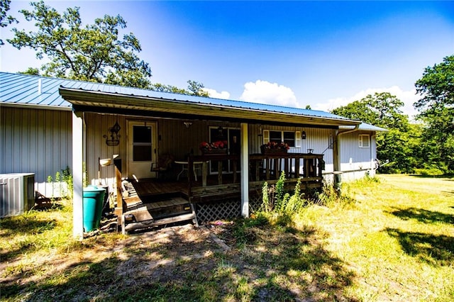 rear view of property featuring a lawn and central AC