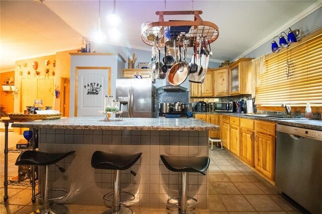 kitchen with vaulted ceiling, a breakfast bar area, appliances with stainless steel finishes, sink, and light tile floors