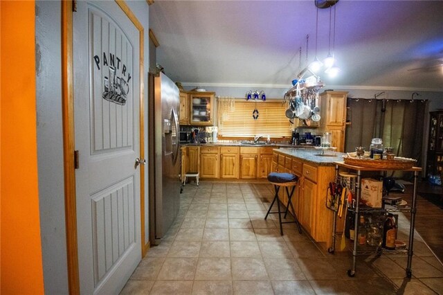 kitchen with a kitchen breakfast bar, crown molding, stainless steel fridge, light tile floors, and sink