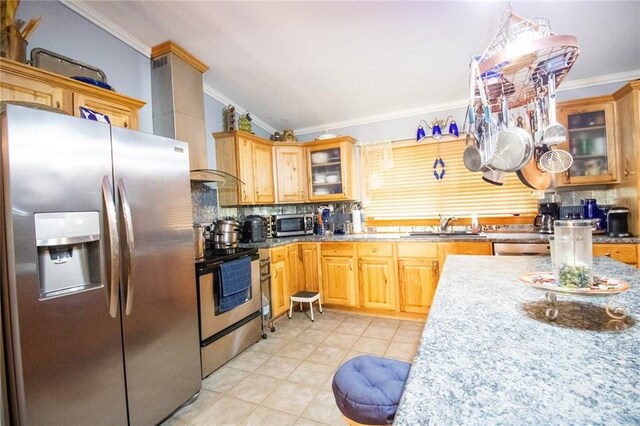 kitchen with stainless steel appliances, backsplash, light tile floors, ornamental molding, and sink