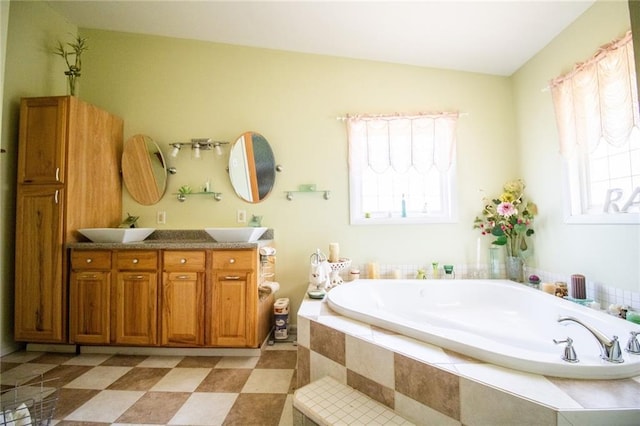 bathroom featuring a relaxing tiled bath, vanity, and tile floors