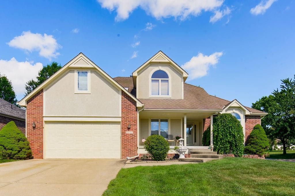 view of front of home with covered porch, a front yard, and a garage