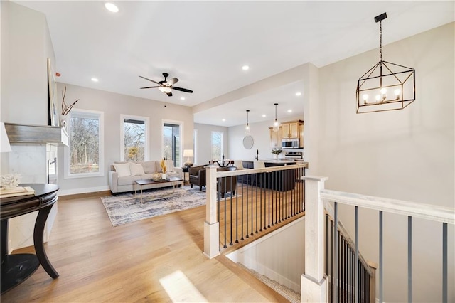 living room featuring ceiling fan with notable chandelier and light hardwood / wood-style floors