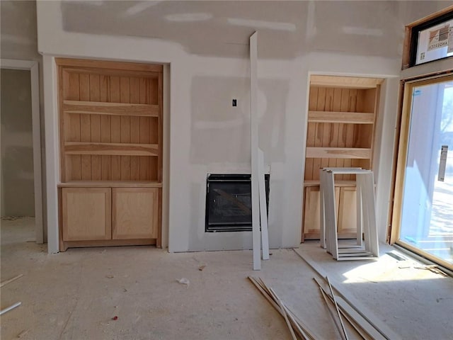 unfurnished living room featuring built in features and a glass covered fireplace