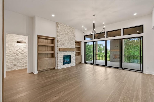 8736 N Lewis Ave, Kansas City, MO 64157 - unfurnished living room with wood finished floors, a chandelier, built in features, a fireplace, and recessed lighting