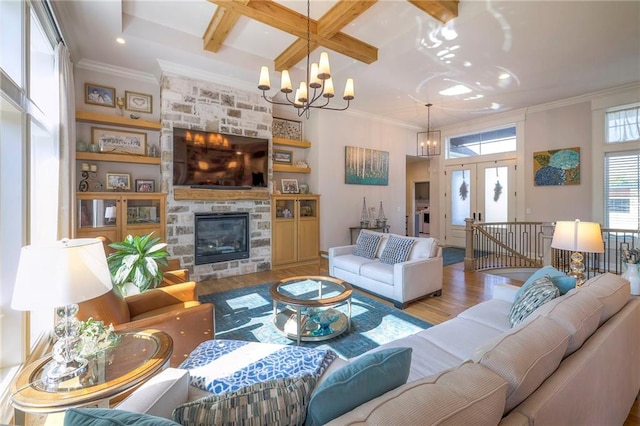 living room with hardwood / wood-style flooring, a chandelier, beamed ceiling, coffered ceiling, and a stone fireplace