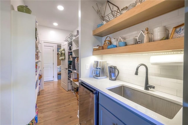 kitchen featuring decorative backsplash, blue cabinets, light hardwood / wood-style flooring, and sink