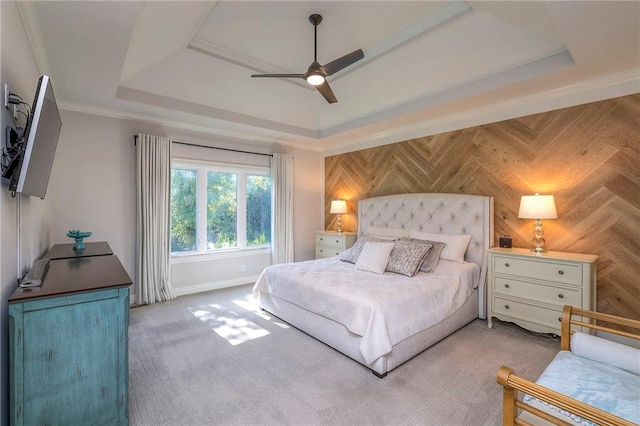 carpeted bedroom with a raised ceiling and ceiling fan