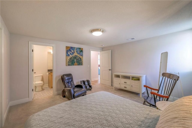 bedroom with light carpet, ensuite bathroom, and a textured ceiling