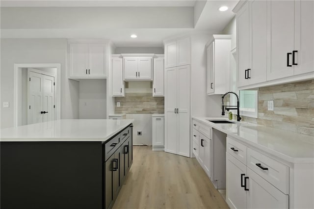 kitchen featuring a center island, sink, white cabinets, and light hardwood / wood-style floors