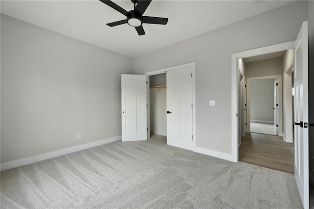 unfurnished bedroom featuring a closet, baseboards, light colored carpet, and a ceiling fan