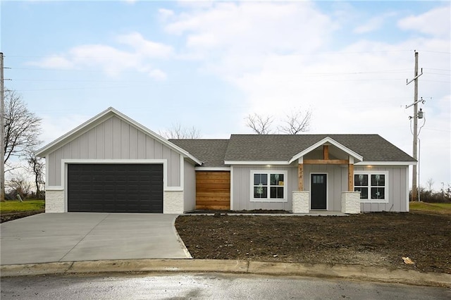 view of front of house with board and batten siding, concrete driveway, a garage, and a shingled roof