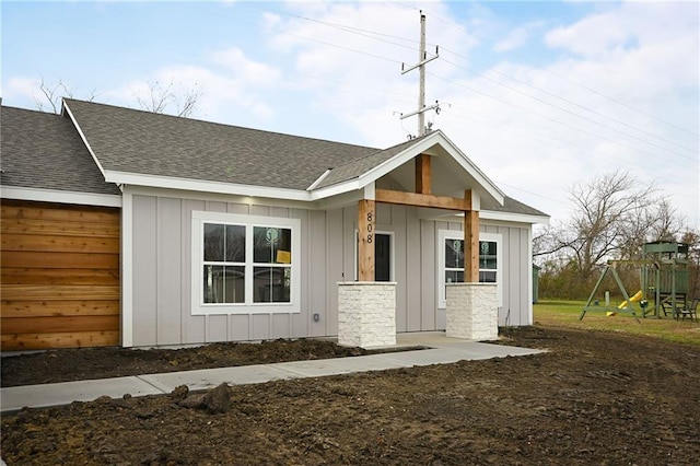 view of front of home featuring board and batten siding, a shingled roof, and a playground