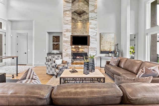 6101 NW 58th St, Kansas City, MO 64151 - living room featuring a high ceiling, healthy amount of natural light, wood finished floors, a tiled fireplace, and baseboards