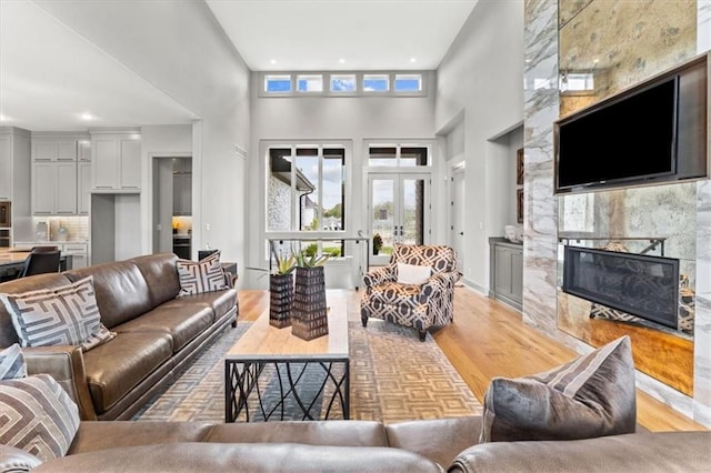 6101 NW 58th St, Kansas City, MO 64151 - living room featuring light wood-type flooring, a high ceiling, a fireplace, and recessed lighting