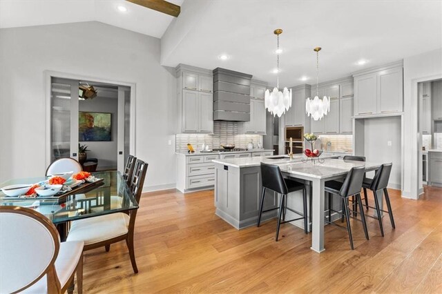 6101 NW 58th St, Kansas City, MO 64151 - kitchen with a sink, light wood-style floors, backsplash, custom range hood, and a center island with sink