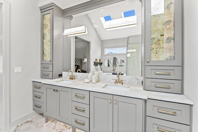 6101 NW 58th St, Kansas City, MO 64151 - ensuite bathroom with a skylight, marble look tiles, double vanity, vaulted ceiling, and baseboards