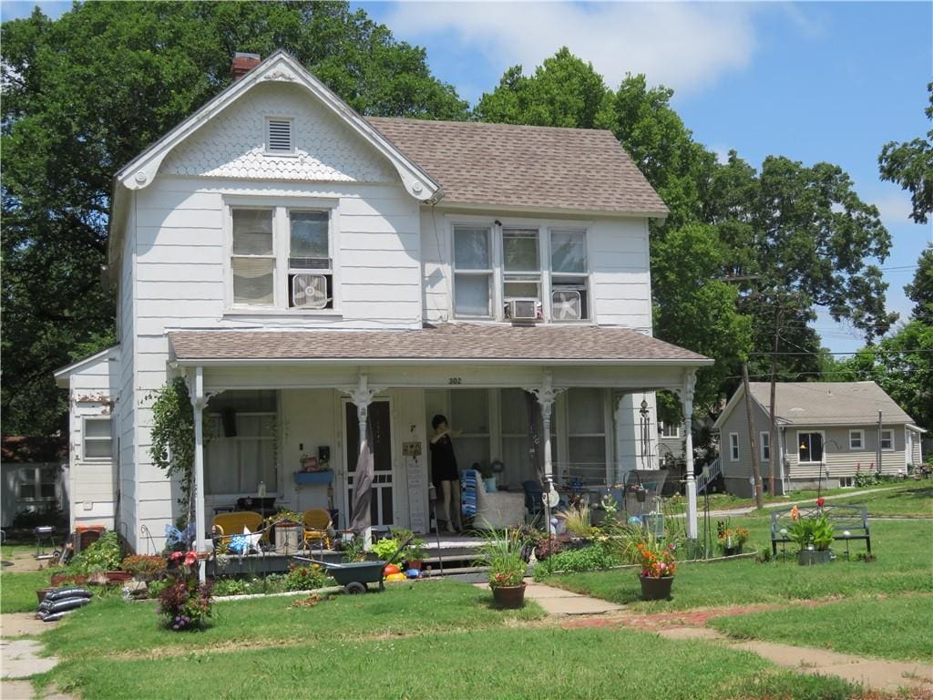 view of front of house with covered porch, cooling unit, and a front lawn