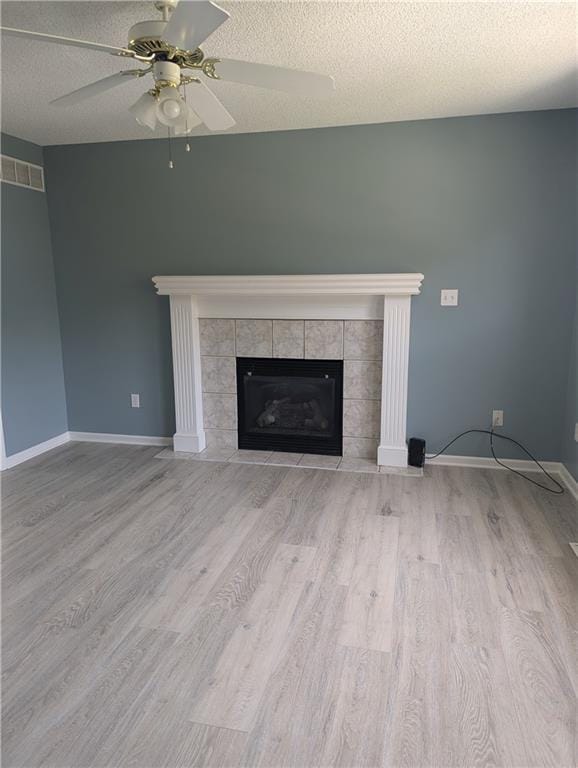 unfurnished living room with a textured ceiling, light wood-type flooring, and a fireplace