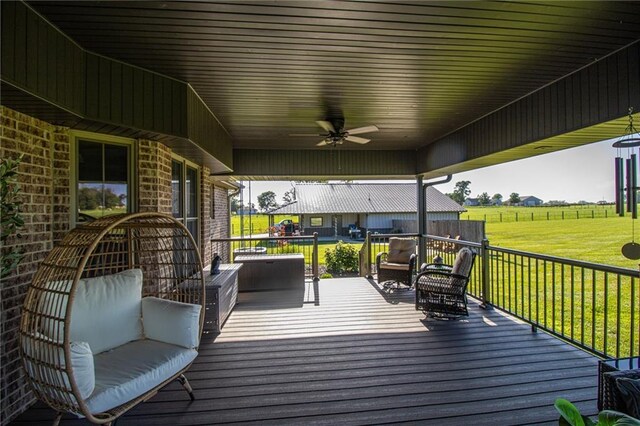 wooden terrace with a lawn, outdoor lounge area, ceiling fan, and a rural view