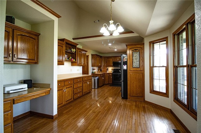 kitchen with appliances with stainless steel finishes, hanging light fixtures, dark hardwood / wood-style flooring, lofted ceiling, and a chandelier