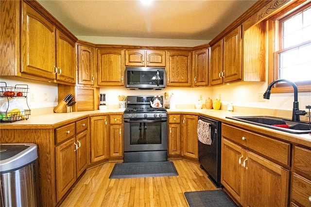 kitchen with gas stove, light wood-type flooring, dishwasher, and sink