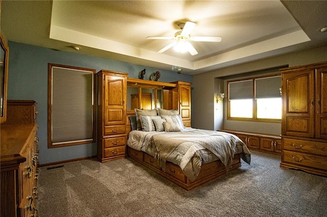 bedroom with ceiling fan, a raised ceiling, and carpet flooring