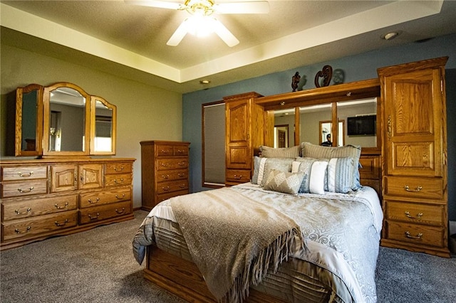 carpeted bedroom featuring a raised ceiling and ceiling fan