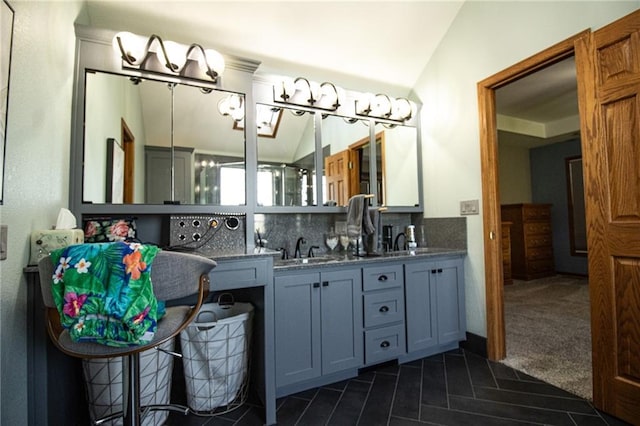 bathroom featuring vanity, vaulted ceiling, and decorative backsplash