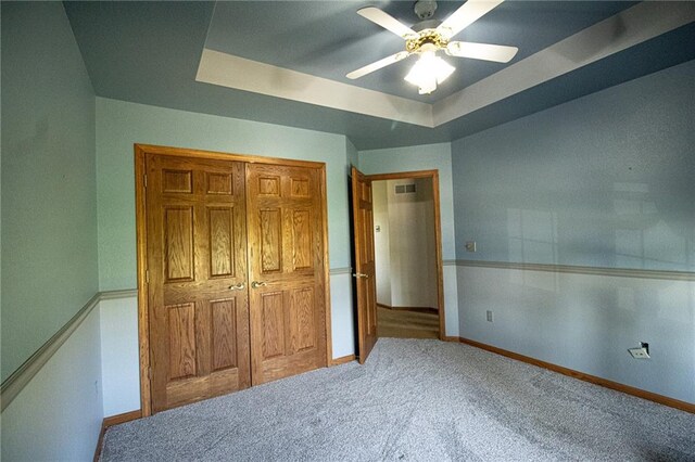 bedroom featuring a closet, a tray ceiling, ceiling fan, and carpet floors