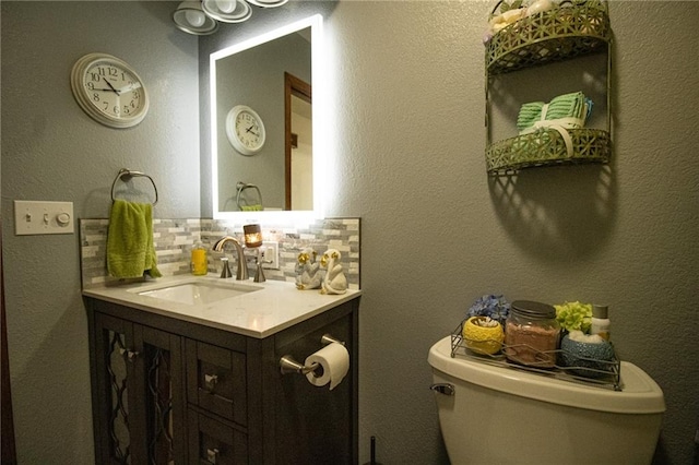 bathroom with backsplash, vanity, and toilet