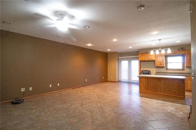 kitchen with hanging light fixtures, a healthy amount of sunlight, and ceiling fan with notable chandelier